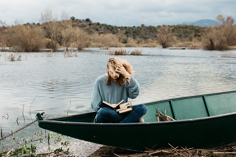 克罗地亚波德戈拉，一名女子在湖上划船看书图片素材