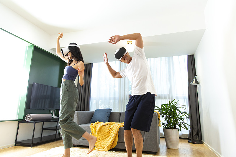 年轻情侣在客厅戴着VR眼镜玩游戏嬉戏图片下载