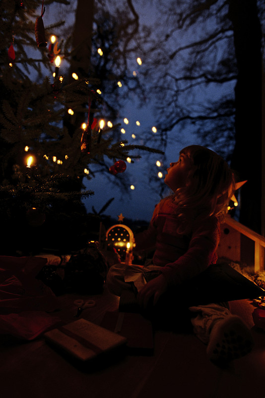 小女孩坐在圣诞树前图片下载