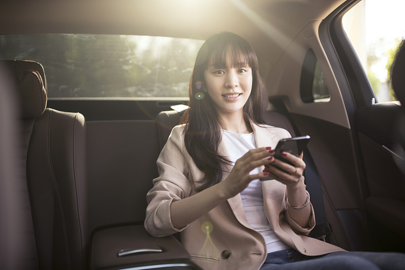 年轻女子在小轿车使用智能手机图片素材