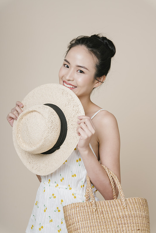 年轻的亚洲旅行者的肖像女人拿着草帽和包。图片下载