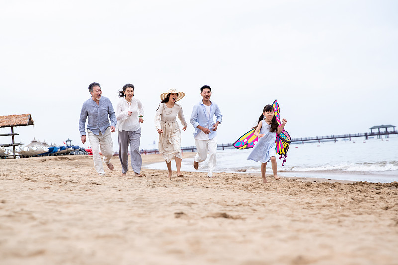 快乐的一家人在海滩上放风筝图片素材