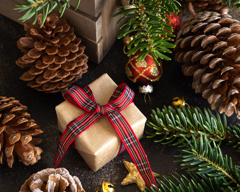 包裹的礼品盒之间的圣诞装饰，松果和绿色的杉树树枝图片下载