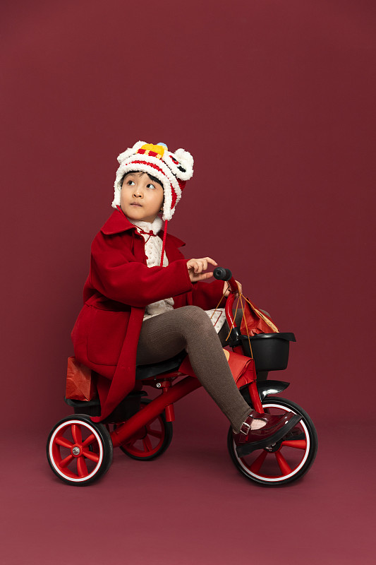 儿童庆祝春节系列：小女孩骑着小三轮车运送春节礼物图片下载