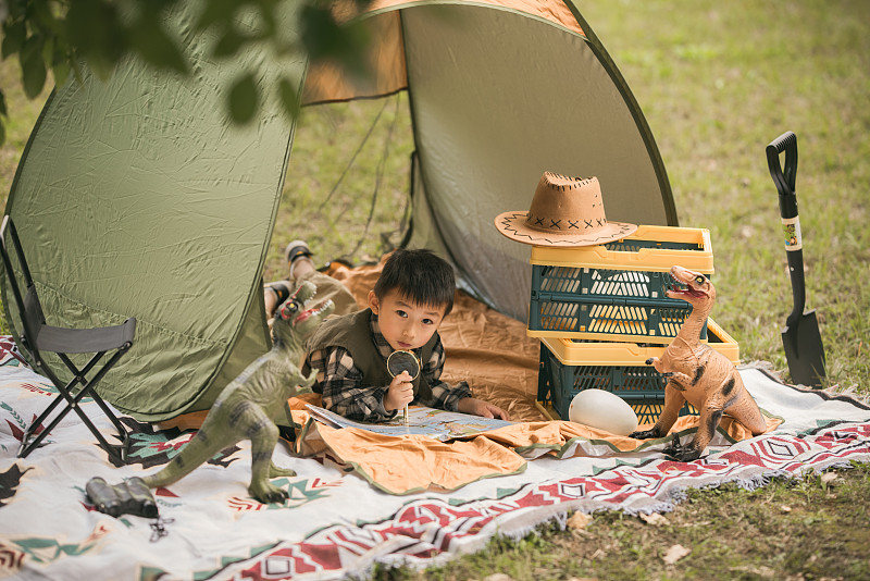 男孩在户外帐篷里玩恐龙玩具图片下载