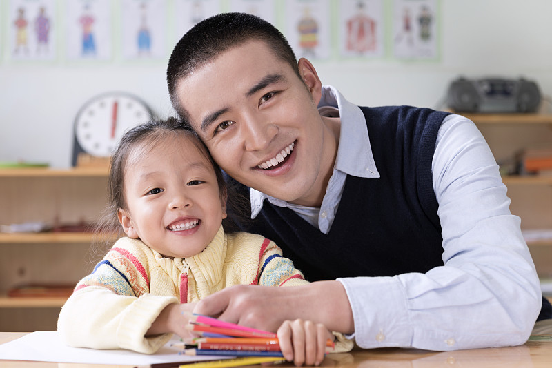 Kindergarten teacher and girl writing图片下载