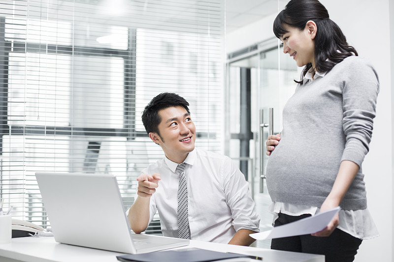 怀孕的商务女士和同事一起工作图片素材