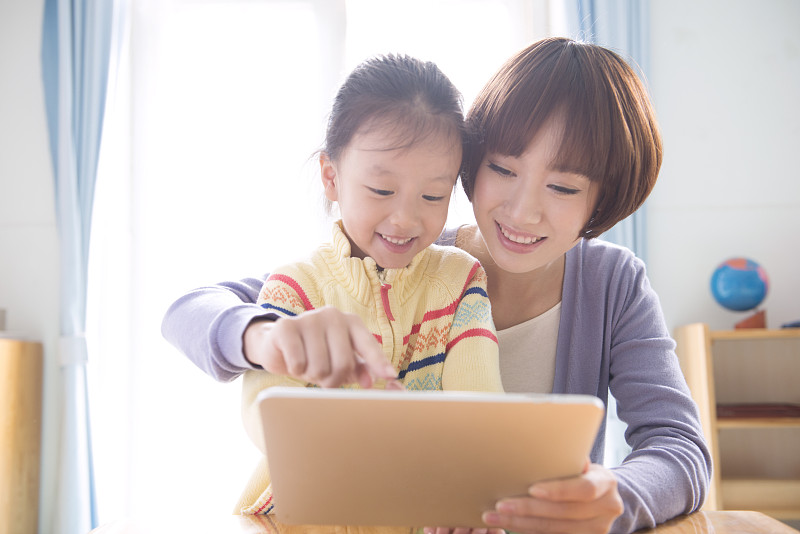 Kindergarten teacher and girl using tablet图片下载
