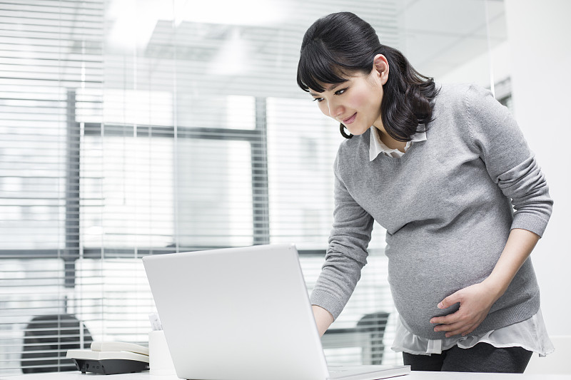 怀孕的商务女士在办公室使用笔记本电脑图片下载