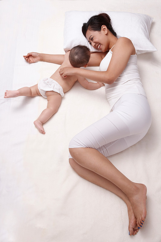 母亲和婴儿躺在床上休息图片下载
