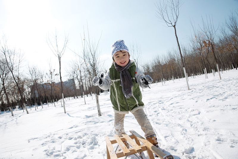 小男孩在雪地上玩耍图片素材