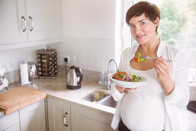 孕妇在家厨房里吃着一碗沙拉图片下载