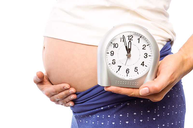 孕妇在白色背景上显示时钟和突起图片下载