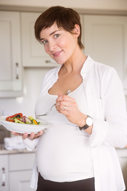 孕妇在家厨房里吃着一碗沙拉图片下载