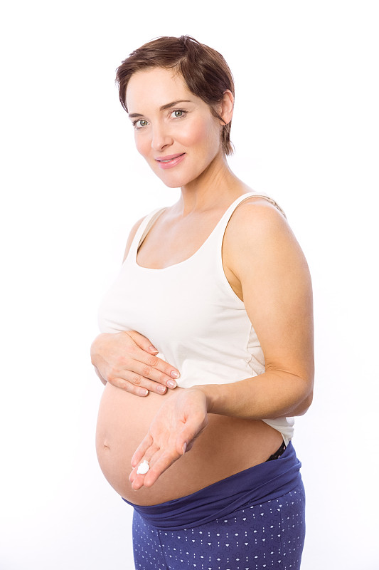一名孕妇在白色背景上展示身体乳霜图片下载