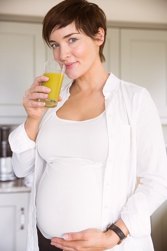 孕妇在家厨房里喝着橙汁图片下载