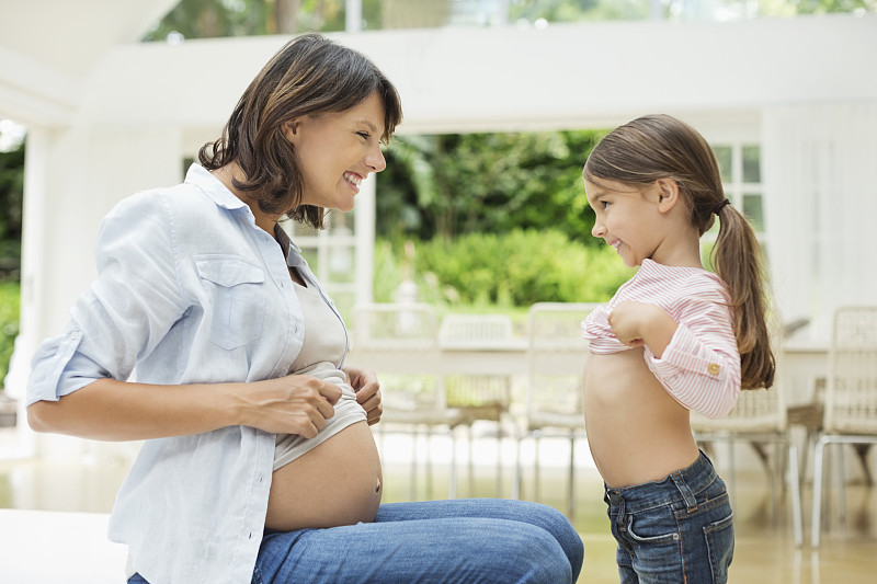 女孩和怀孕的母亲比较肚子图片素材