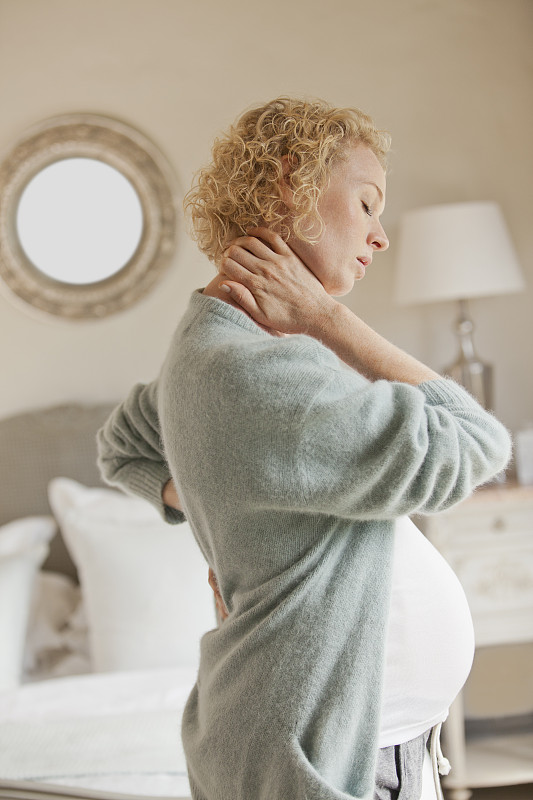 孕妇抱着脖子和背部疼痛图片素材