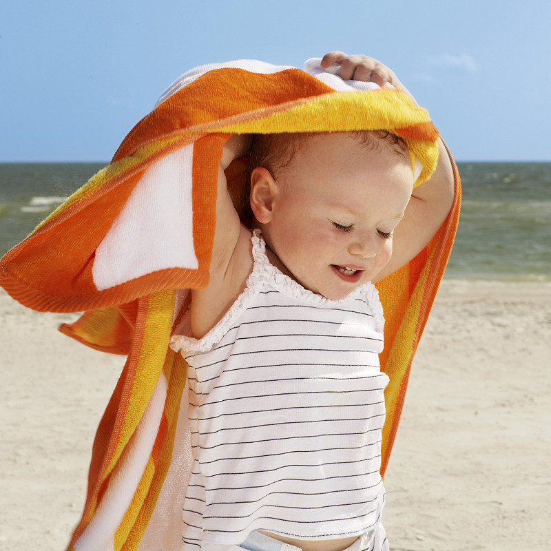 可爱的小女孩拿着毛巾在海滩上图片下载