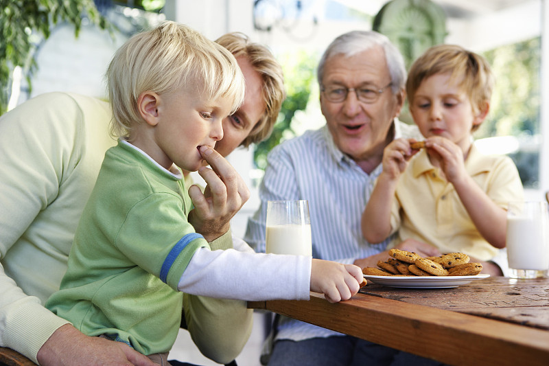 和父亲在餐桌上吃饼干和牛奶的男孩图片下载