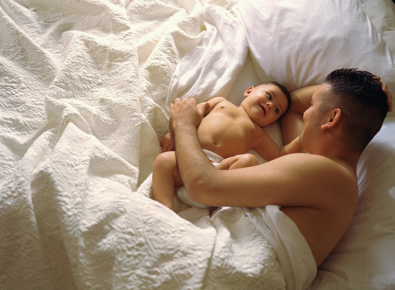 躺在床上的父亲和他的婴儿儿子图片下载