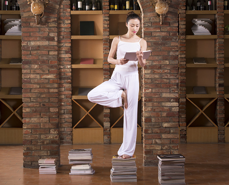站在书上练习瑜伽的青年女子图片下载