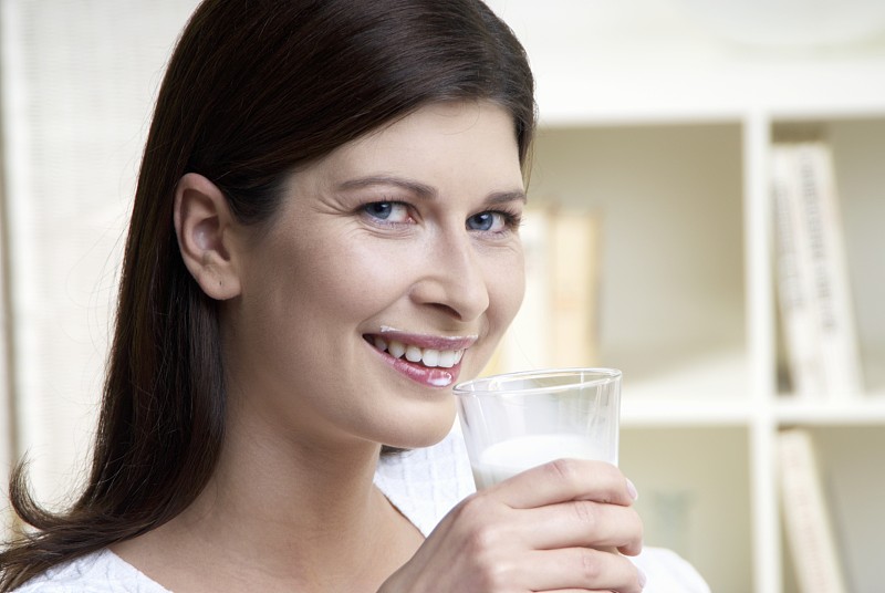 女人用圆圆的牛奶嘴捧着一杯牛奶图片下载