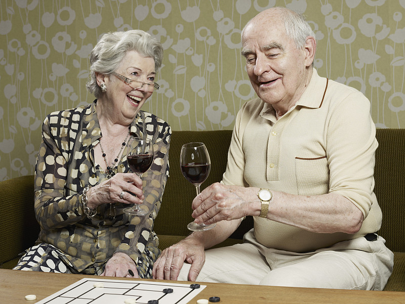 老夫妇喝着红酒在沙发上敬酒图片下载