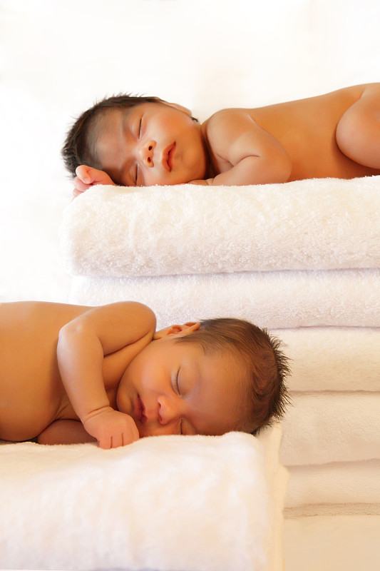 双胞胎宝宝睡在成堆的毛巾上图片下载