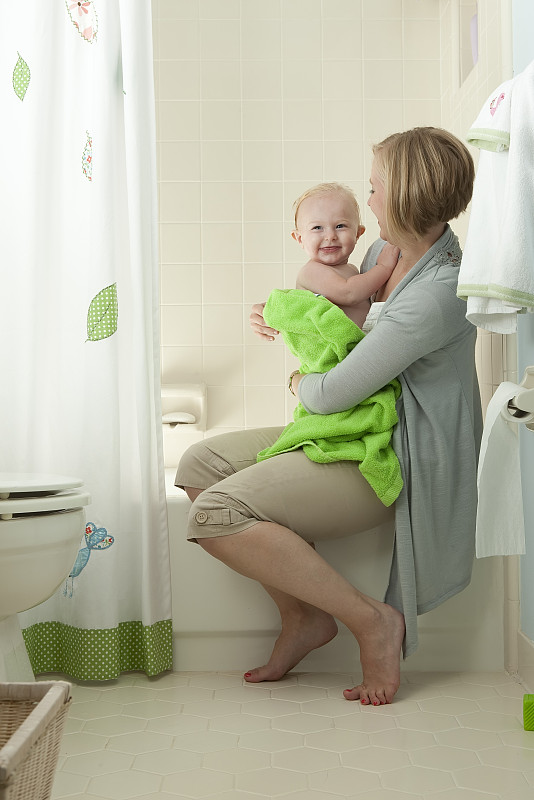 母亲从浴缸中拥抱孩子。图片下载