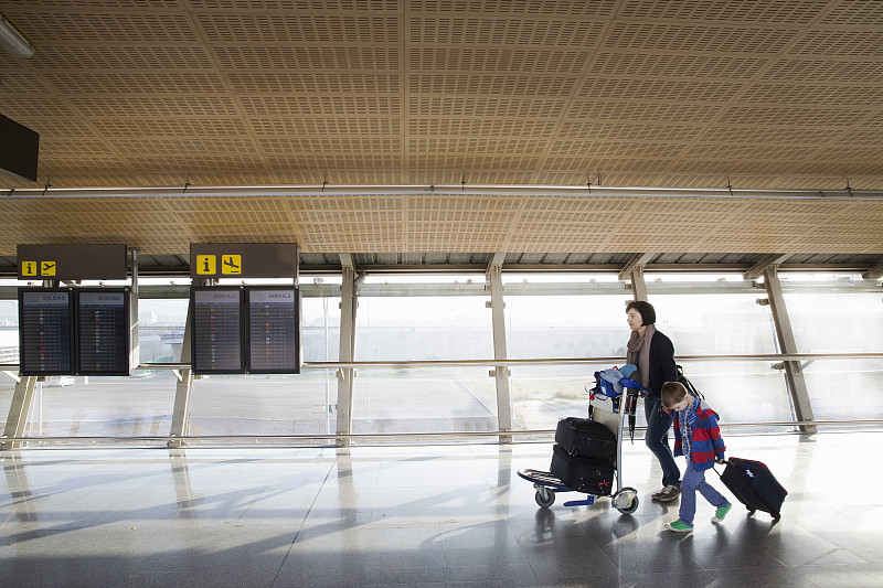 母亲带着年幼的儿子和行李在机场图片下载