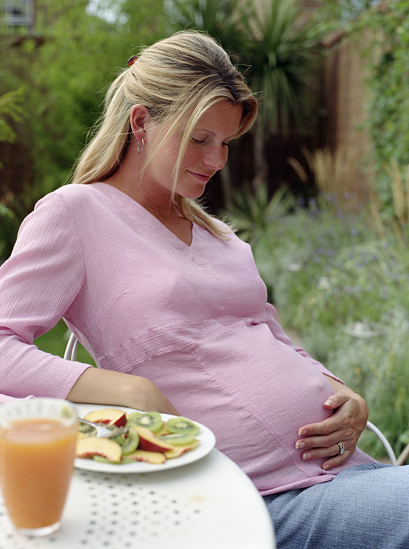 孕妇在户外吃早餐，看着肚子图片下载