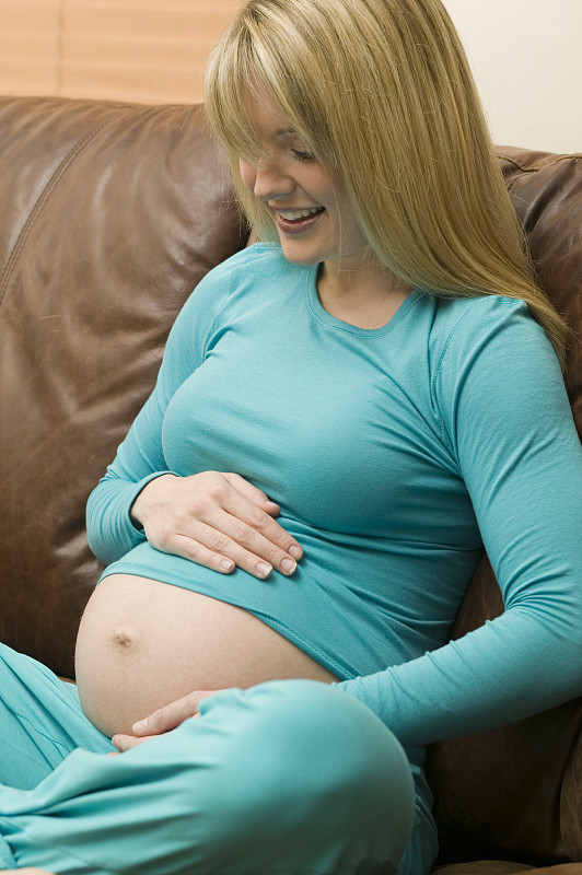 一个孕妇在客厅的沙发上休息图片下载