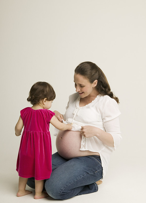 女婴(15-18个月)抚摸孕妇的腹部图片下载