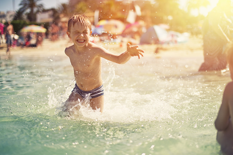 小男孩在海滩上玩海溅水图片素材