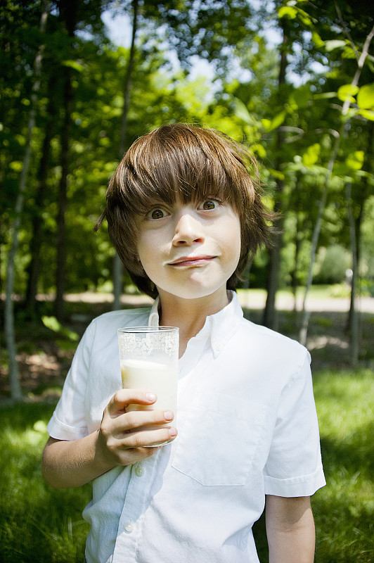 男孩在树林里喝奶昔，做鬼脸图片下载