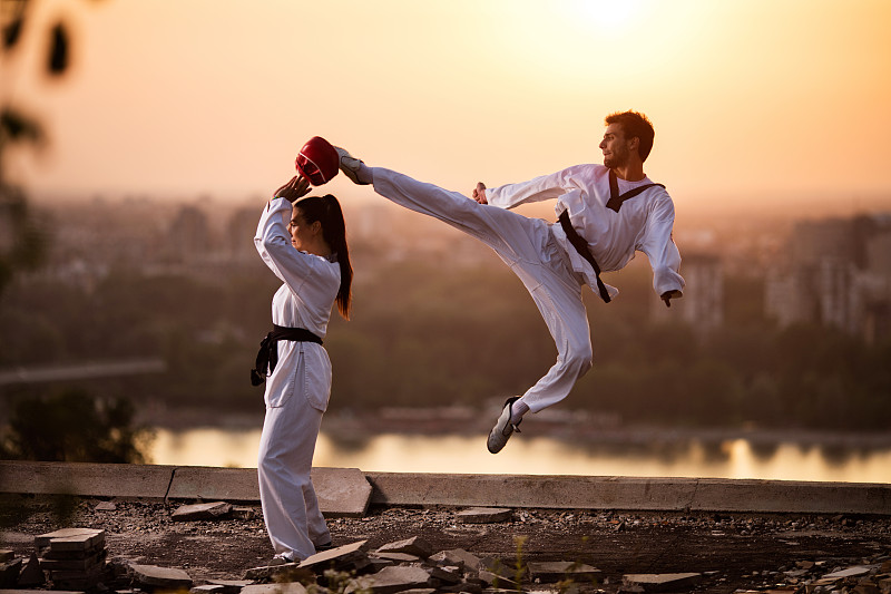 武术家与女性伙伴在日落练习格斗。图片下载