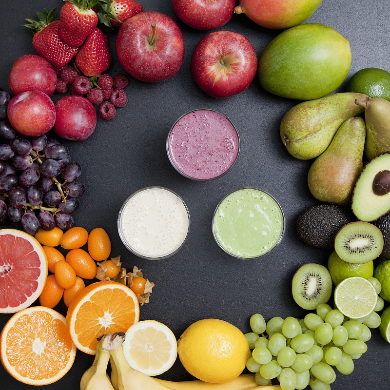 Overhead still life of variety of fruit surrounding fresh smoothies图片素材