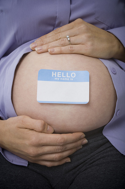 一个孕妇腹部有一个名字标签的中段视图图片素材