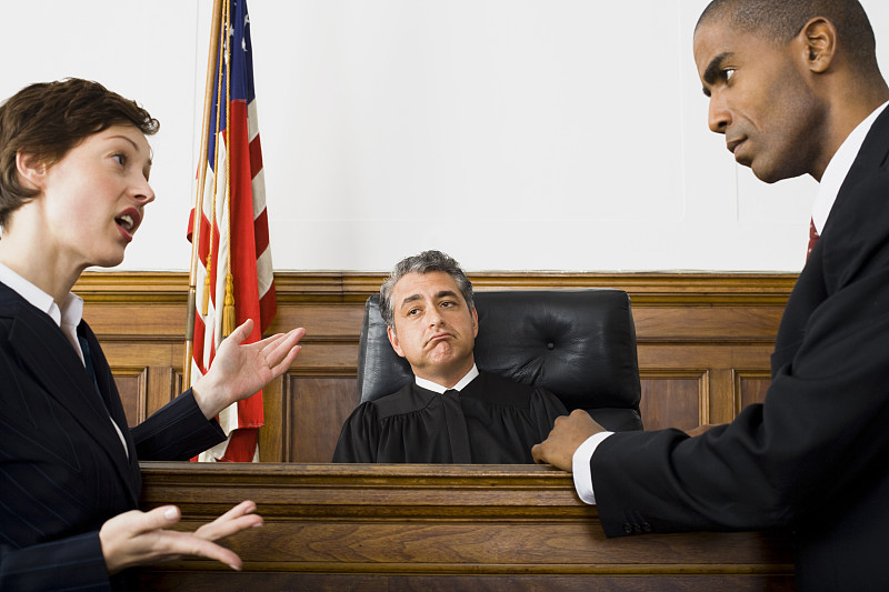 两名律师在法庭上面对面地站在一名男性法官面前图片素材