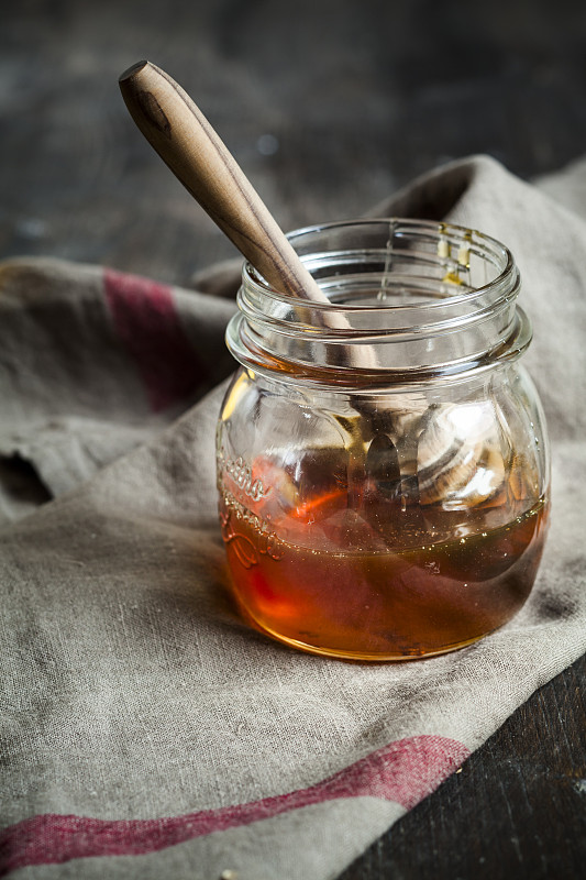 蜂蜜在玻璃杯和木制蜂蜜匙图片下载