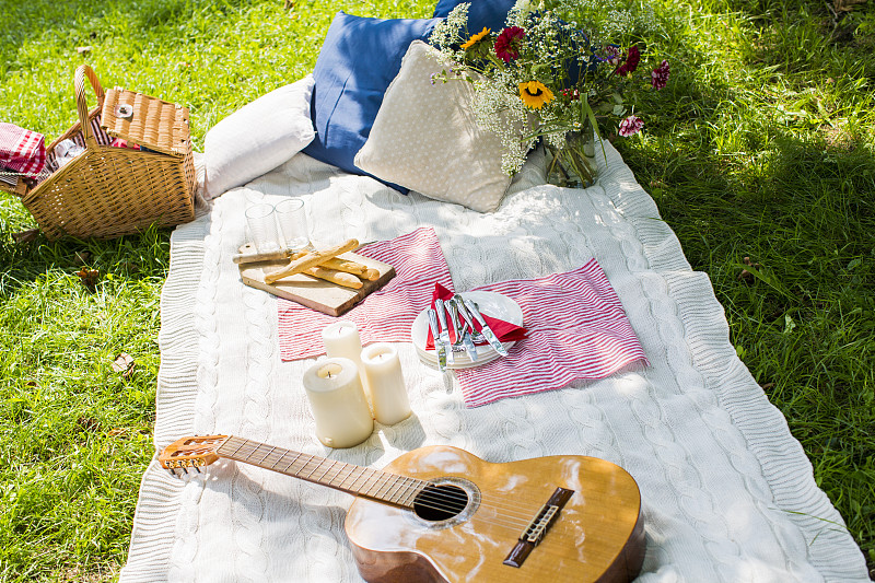 野餐毯，吉他，蜡烛和垫子在草地上图片下载