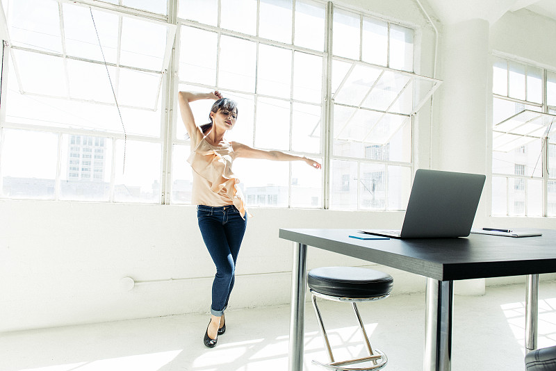 女商人在办公室窗户旁跳舞图片下载