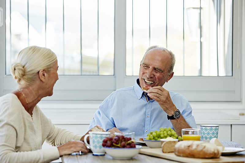 一对幸福的老年夫妇在餐桌上吃早餐图片下载