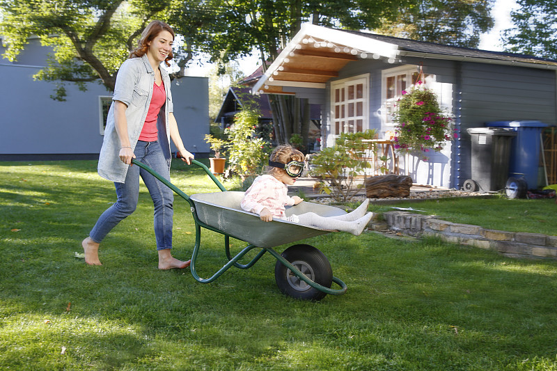 母亲与女儿在花园手推车的乐趣图片下载