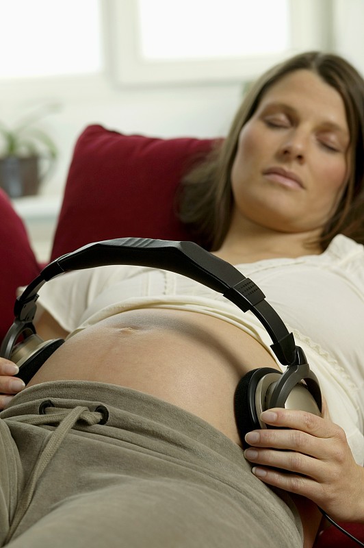 孕妇躺在沙发上，肚子上放着耳机图片下载