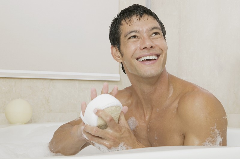 一个年轻人在浴缸里拿着丝瓜络的特写图片下载