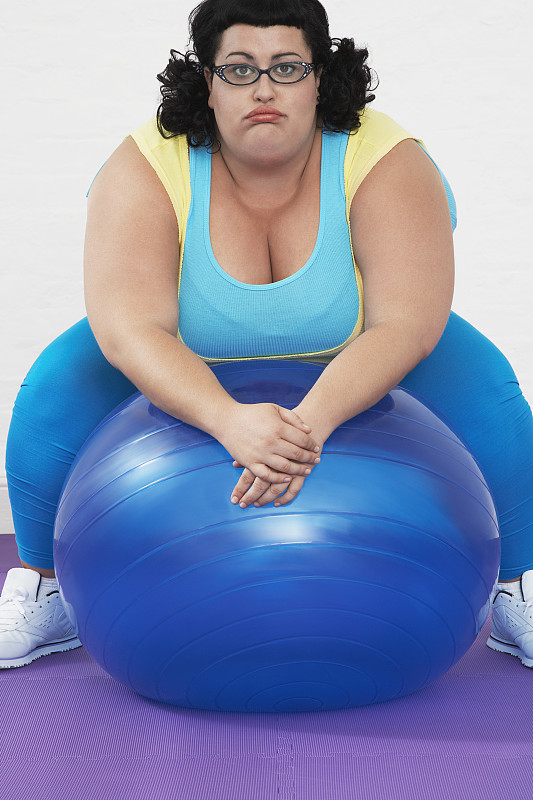 超重女子在健身球上休息图片下载