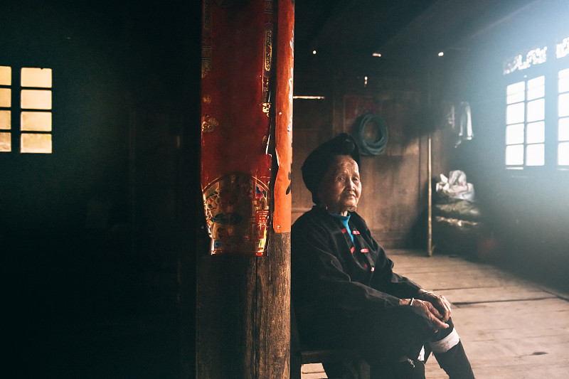 黑暗的房间里，一个中国老妇人坐在凳子上图片下载