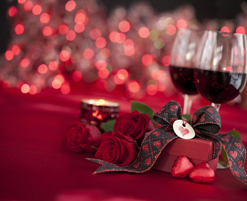 情人节红玫瑰和红酒与礼物在散焦灯光的背景图片下载